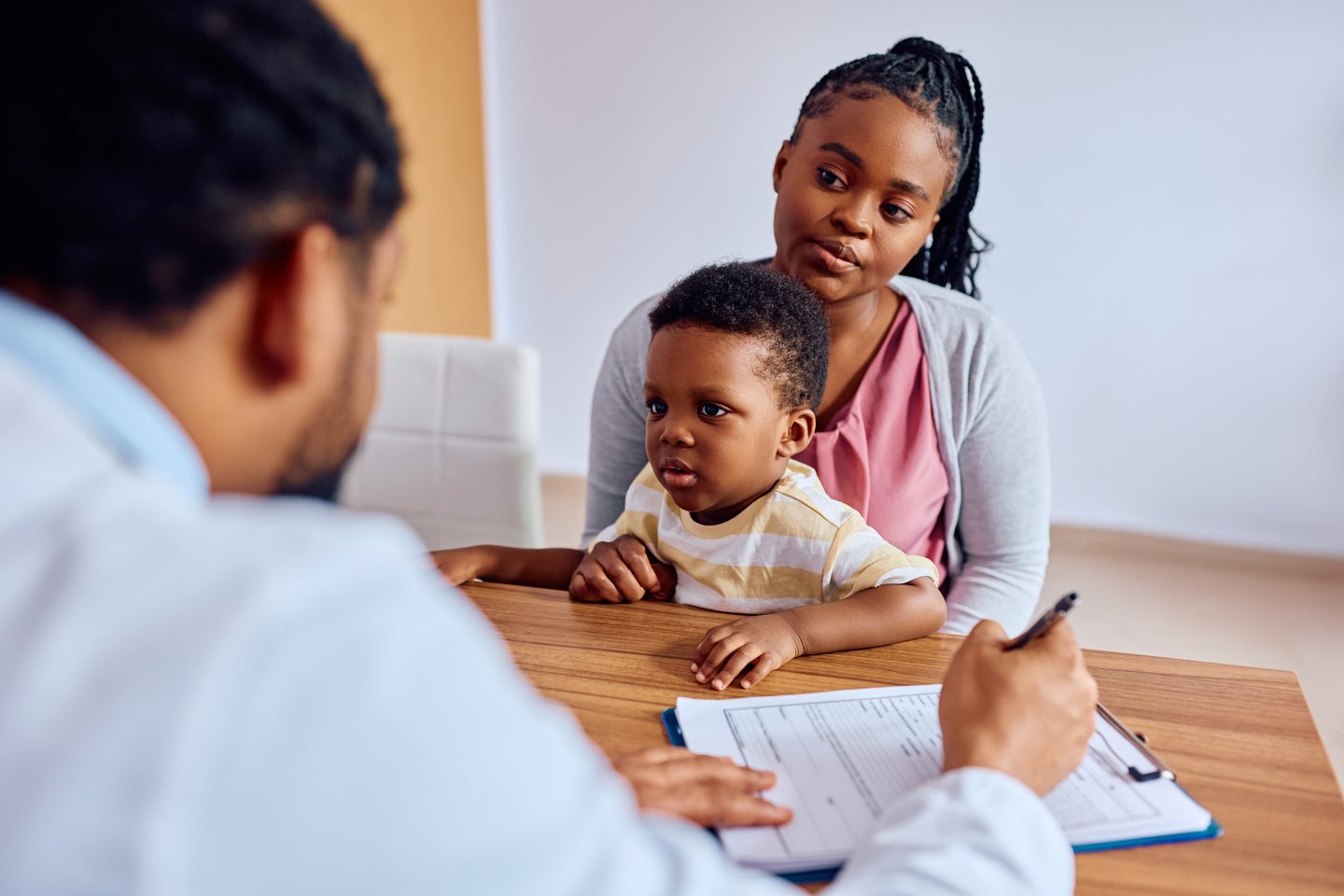 Picture of a mother and her young son talking to a doctor in a medical setting