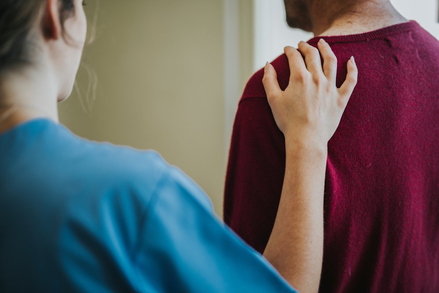 Female nurse placing a reassuring hand on a males shoulder