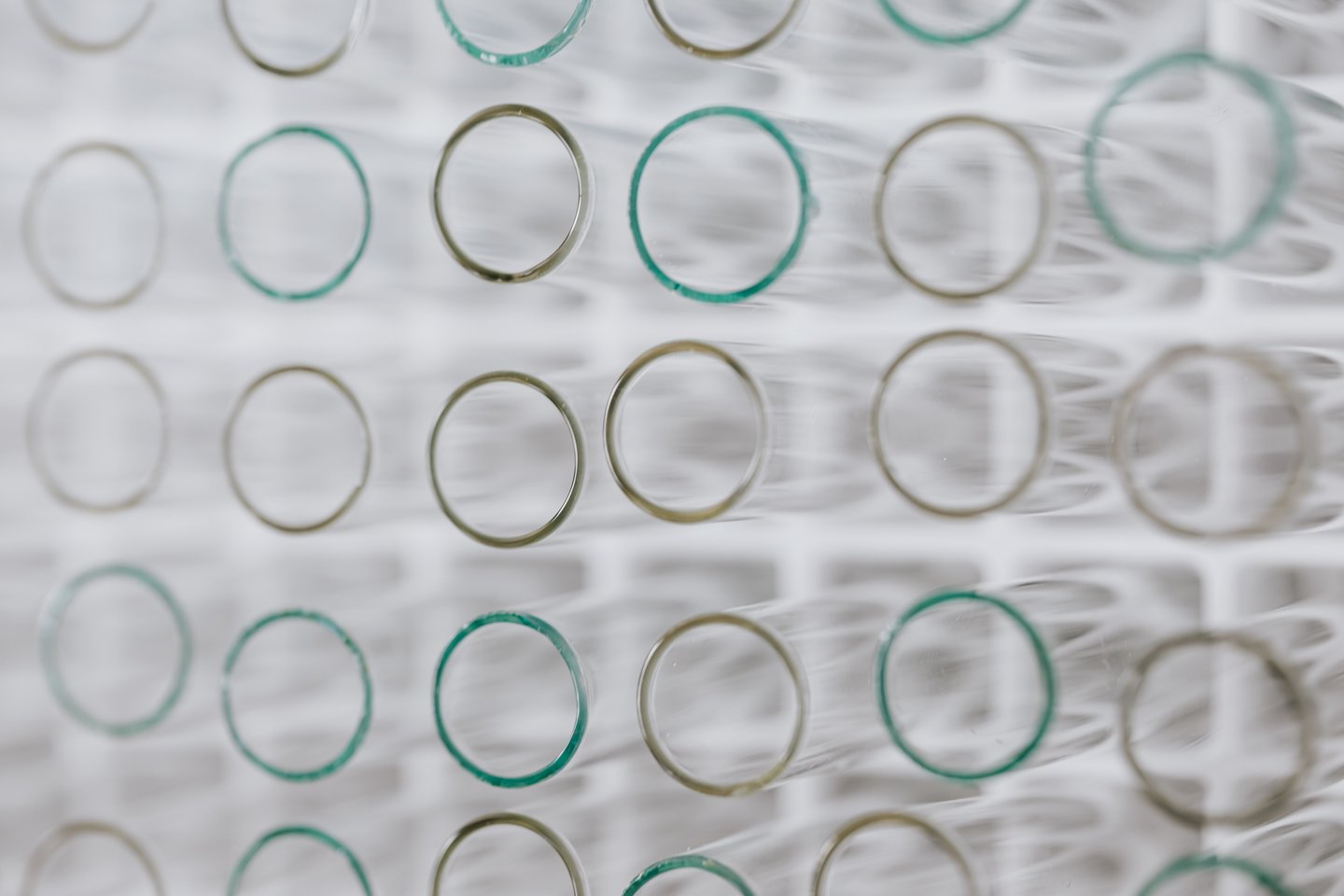 A close-up view of neatly arranged glass test tubes, aligned in rows with their circular openings facing the camera, creating a geometric pattern.