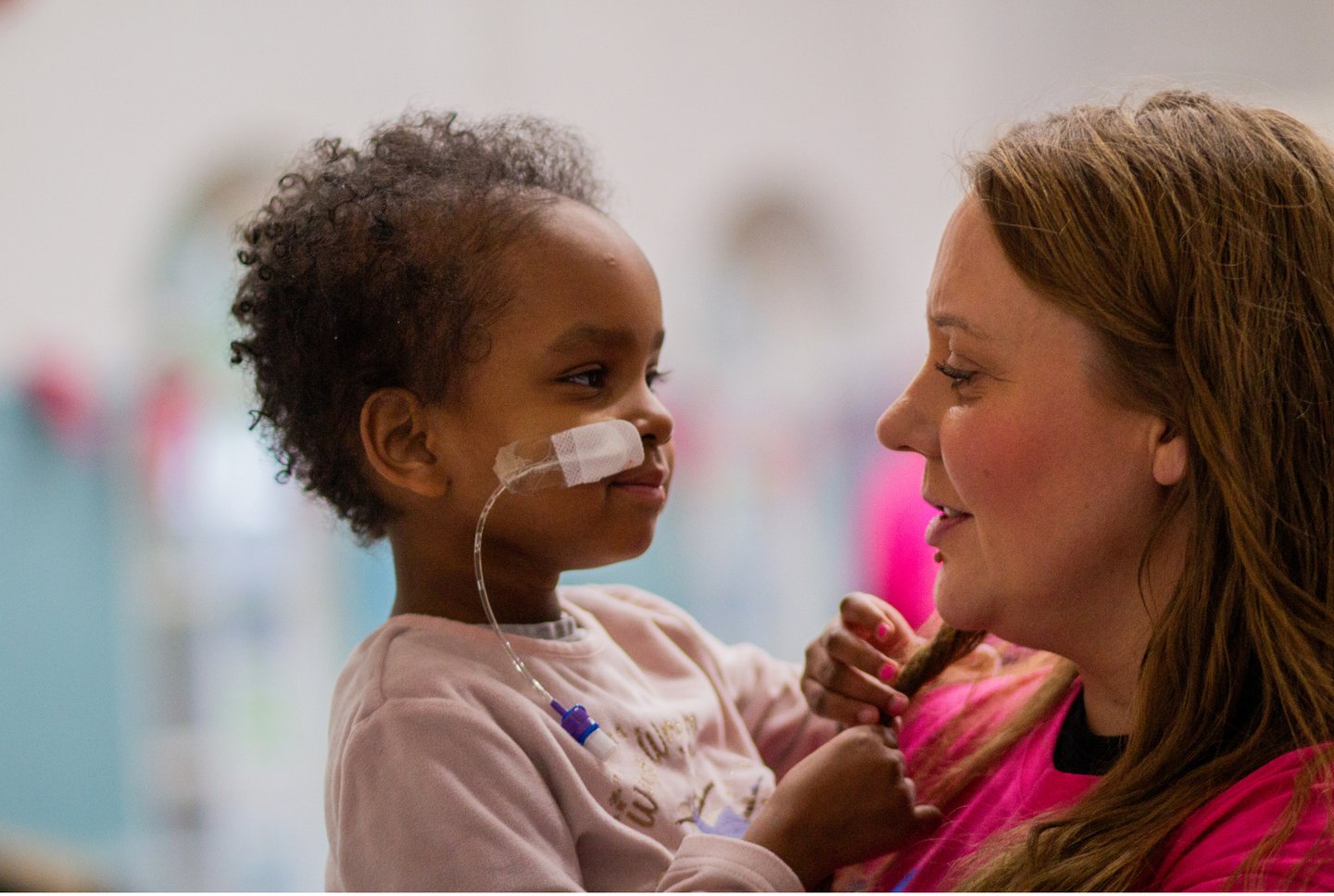 Solving Kids' Cancer UK Family Support Worker Hayley holding a child at a charity event.