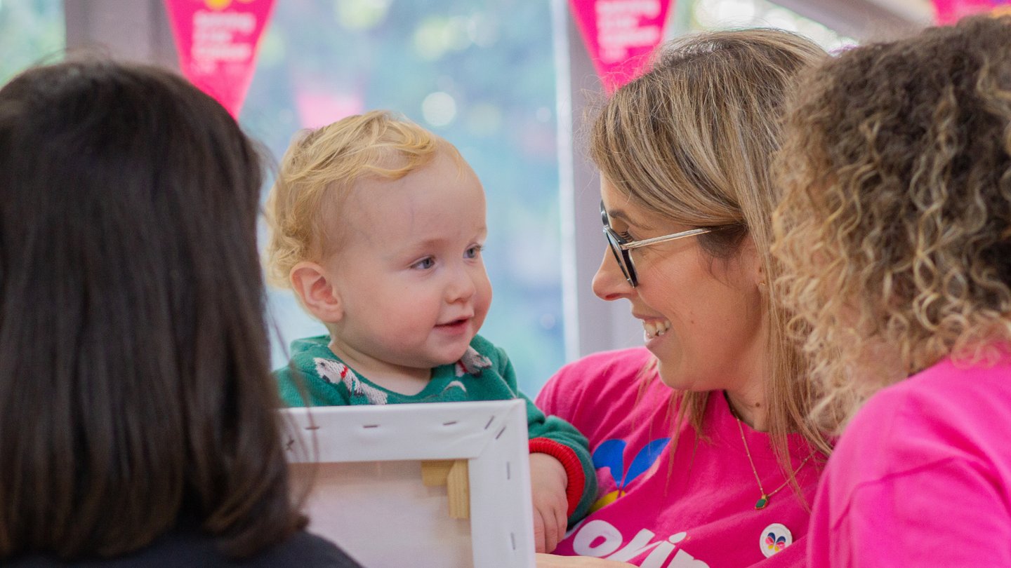 Photo of Solving Kids' Cancer UK Family Support Coordinator smiling and talking with a family