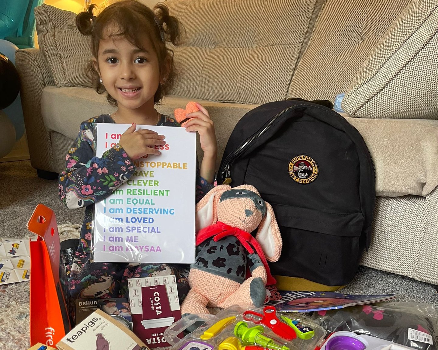 Photo of little girl with the content of her Family Support Bag from Solving Kids' Cancer UK