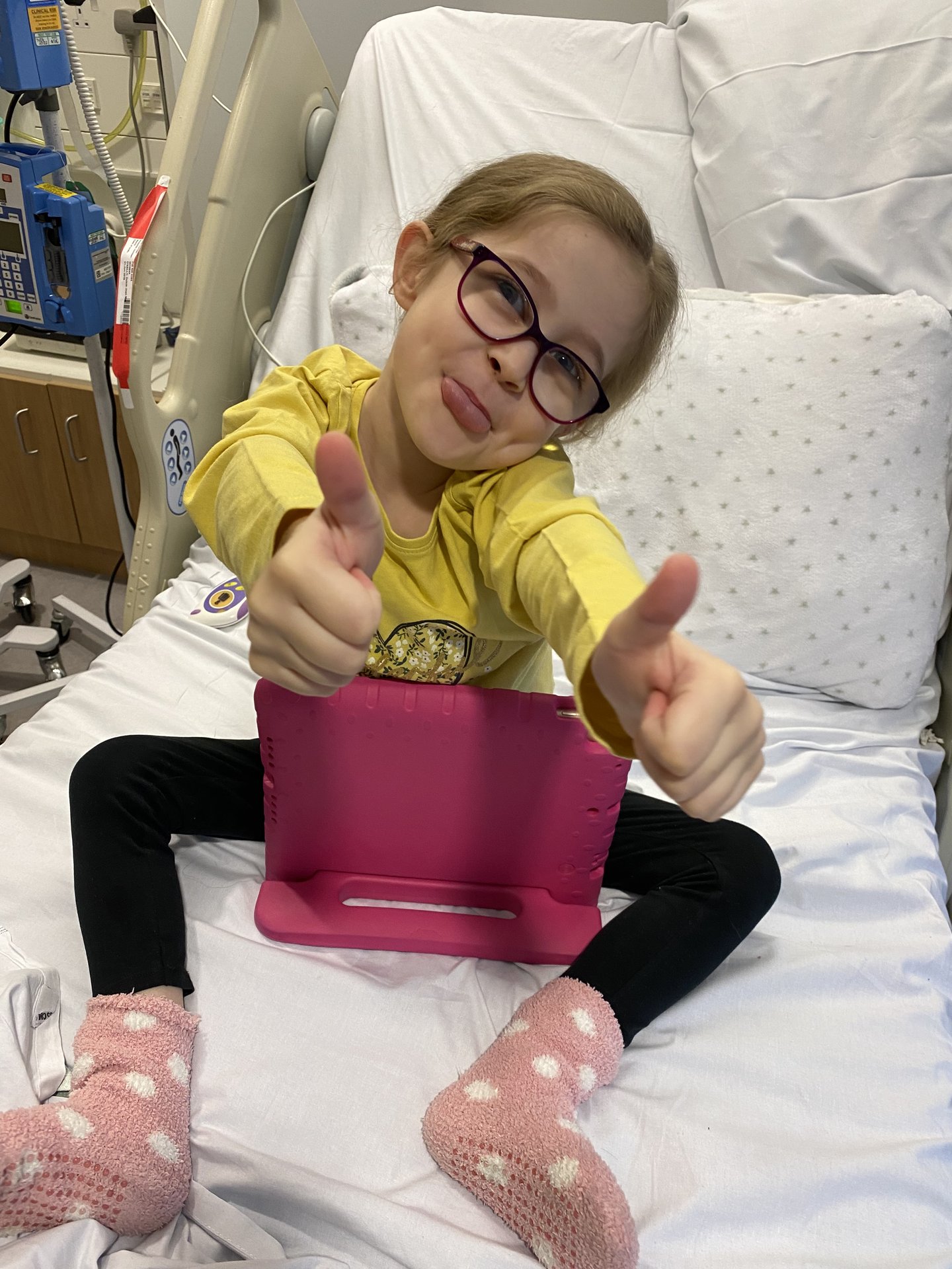 Dulcie giving the thumbs up sat on her hospital bed