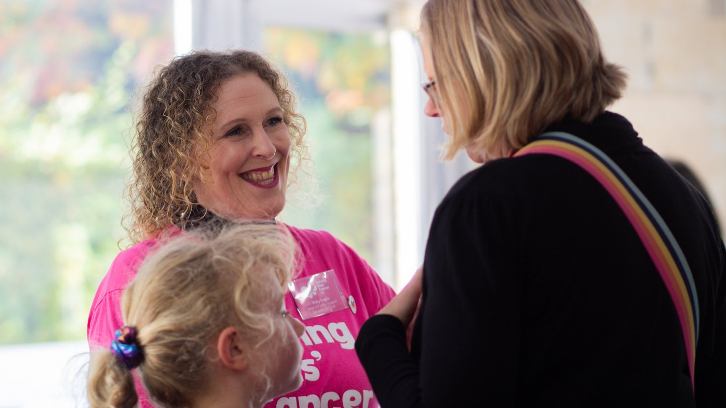Photograph of Solving Kids' Cancer UK's Head of Family Support smiling and talking with a family.