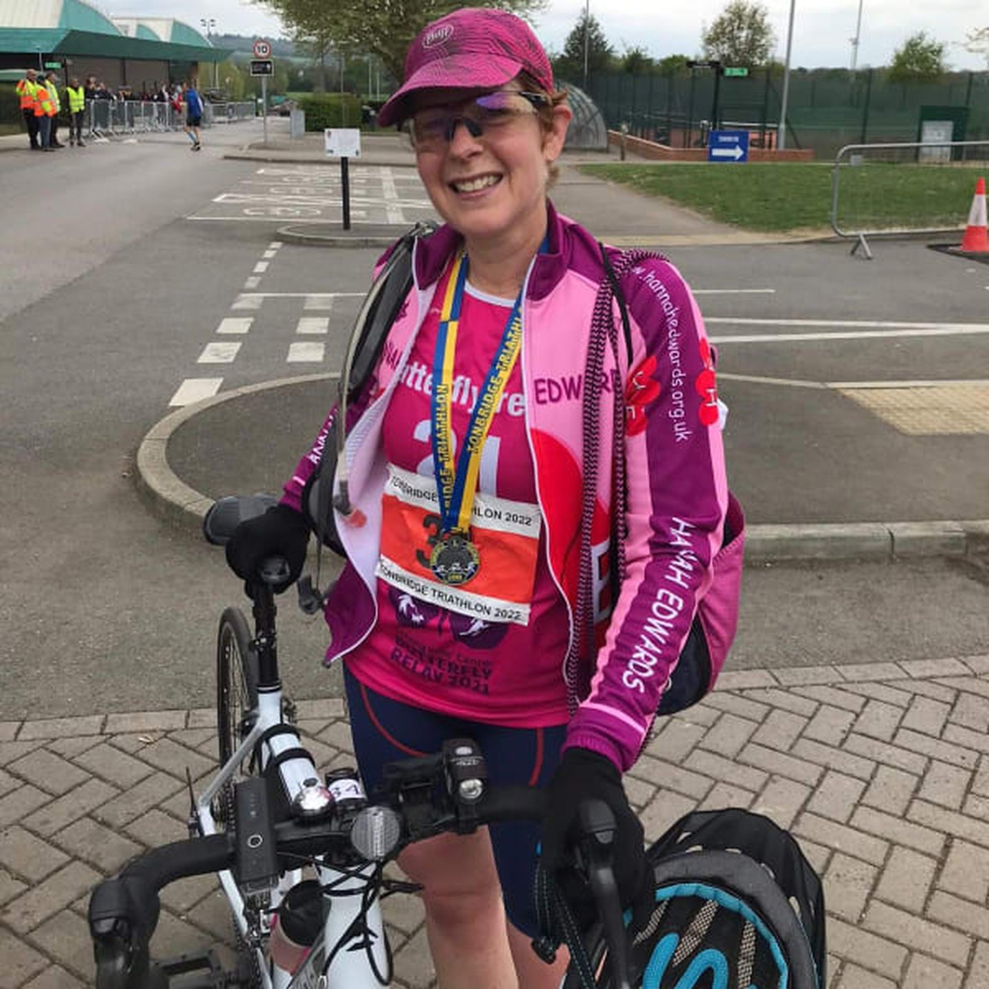 Clare in pink charity cycling kit standing beside a road bike after completing an event