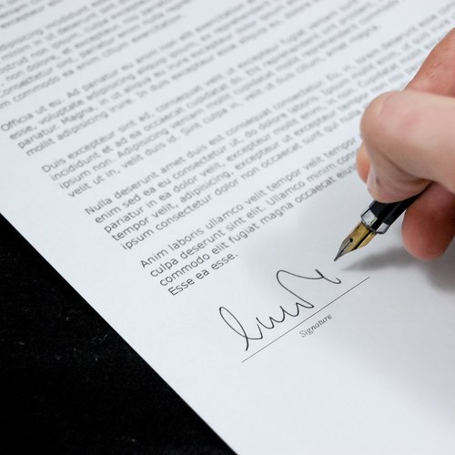 Hand holding a pen ready to sign a document.