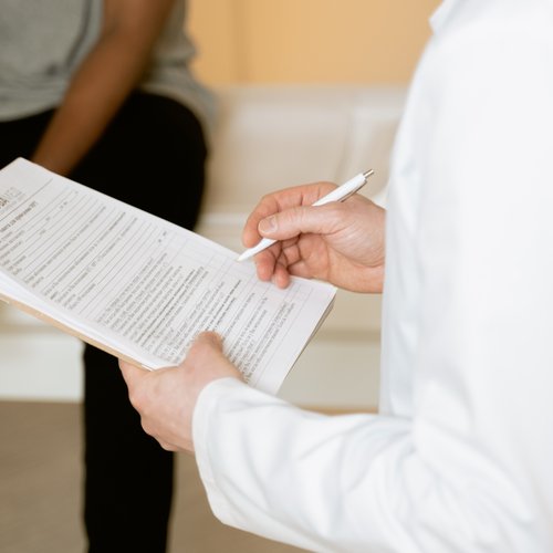 A doctor signing some papers in front of a patient.