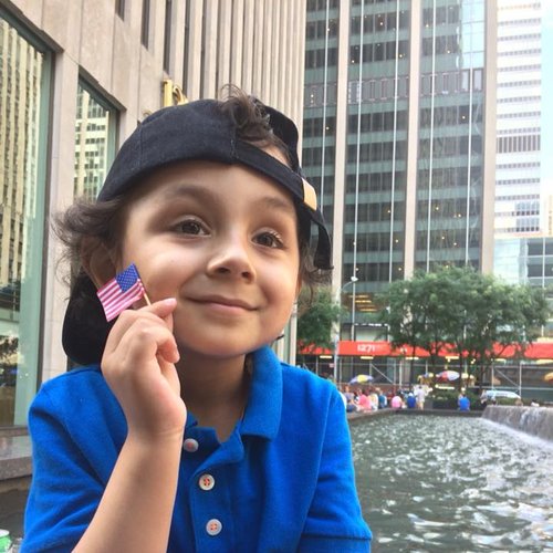 A smiling child holding up a small American flag