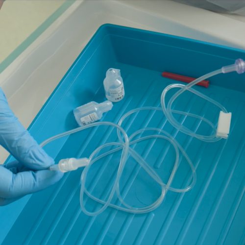 Gloved hand handling a medical syringe with tubing attached